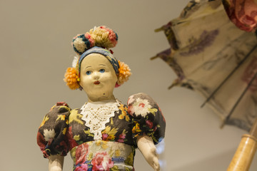 An ancient doll with a parrot in the background.