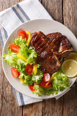 Spicy T-Bone steak with fresh vegetable and lemon close-up. Vertical top view