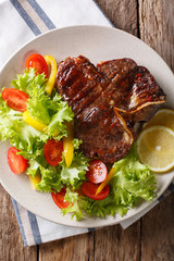 T-bone beef steak with fresh vegetable salad closeup. Vertical top view