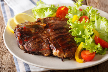 T-Bone steak with fresh vegetable salad and lemon close-up. Horizontal