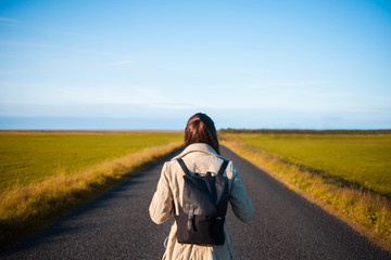 Woman tourist with backpack on the background road. Toward the goal