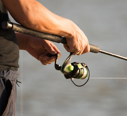 Fishing rod in the hands of a fisherman on the river