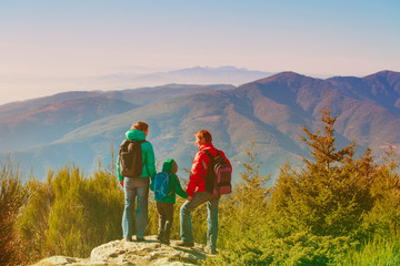 family with little child hiking in mountains