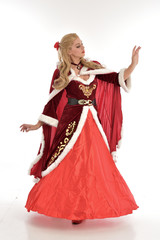full length portrait of pretty blonde lady wearing red and white christmas inspired costume gown, standing pose on white background.