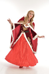  full length portrait of pretty blonde lady wearing red and white christmas inspired costume gown, standing pose on white background.