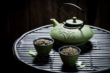 Foto op Aluminium Fresh tea with teapot on black bamboo table © shaiith
