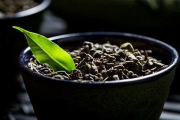 Closeup of grains green tea on black teacup