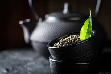 Crédence de cuisine en verre imprimé Theé Closeup of leaf green tea in teacup on black rock