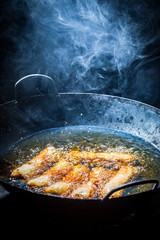Closeup of fresh spring rolls frying in black wok