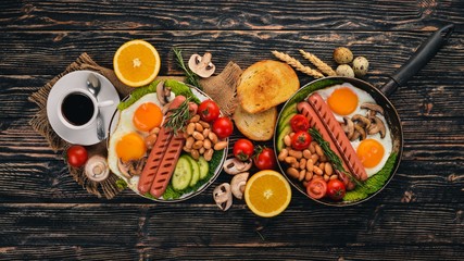 English breakfast - fried egg, beans, tomatoes, mushrooms, bacon and toast. Top view. On a wooden background.
