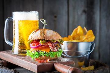 Cold beer and hamburger made of beef, cheese and vegetables