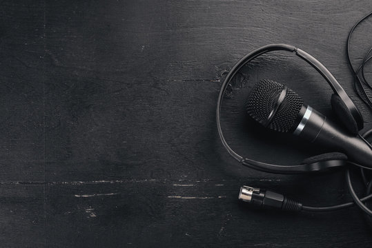 Headphones and microphone on a wooden black table. Studio. Top view. Free space for text. Copy space.
