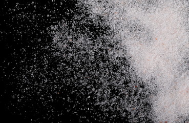 Himalayan salt grains isolated on black background, top view