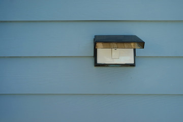 Bell switch with rain cover on the pastel light blue wooden wall in front of house
