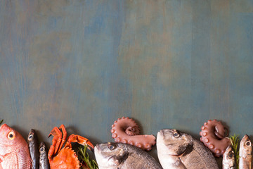 Top view on fish and seafood on blue table with copy space.