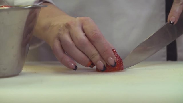 Cooking in the restaurant. Close up serving dishes. Female hands cutting strawberries on a plastic board
