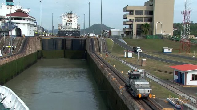 Panama mule pulls ship into Miraflores lock Panama Canal. Container ship MSC Carmen is in the background 