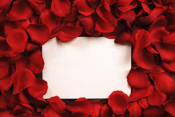 White blank card in red roses petals close up, copy space. Valentines day, love letter, wedding invitation concept