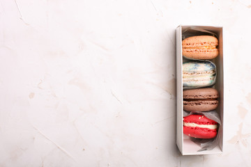 Stylish gift box with french macaroons and cotton flowers on white background, copy space