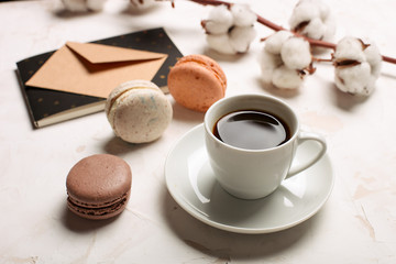 French macaroons with coffee cup, notebook, envelope and cotton flowers on white table