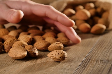 A hand that grabs some almonds. Concept of: beauty, oils, creams, wellness.