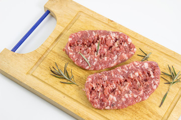 Fresh pork sausages isolated on white background, -raw sausage for cooking on cutting board with rosemary on a white background, top view