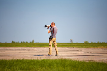 A photographer with two cameras in a summer field takes pictures of nature.