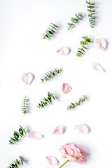 floral pattern with rose petals and eucalyptus on white table to