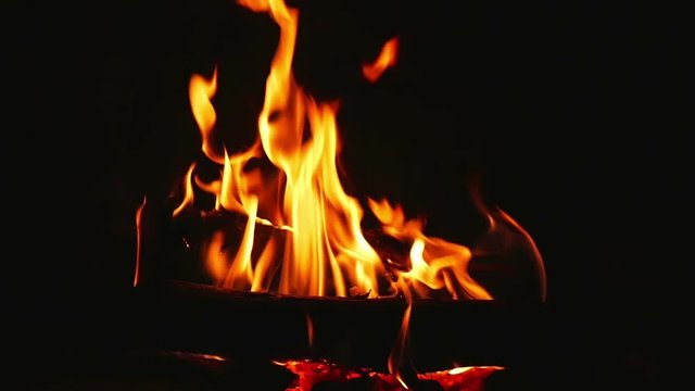 Orange flames from burning logs in indor open fireplace in super slow motion.