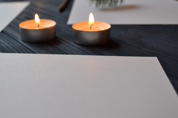 White paper and lighted candles on the table. Minimalism. Stylish background.