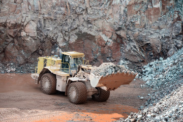 Earthmover in an active quarry mine of porphyry rocks. digging.