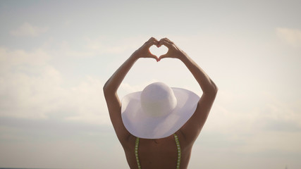beautiful girl making a hart by hands, background: Love, sky, sunshine