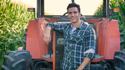 Portrait of a beautiful young farmer (student) working in the field with a tractor working in a...
