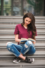 Young pretty woman sitting and reading a book enjoys of rest