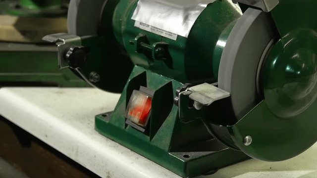 Grinding flat bar steel on table circular electric grinder in super slow motion. Pushing the steel plate to hard and making machine to stop under preasure.