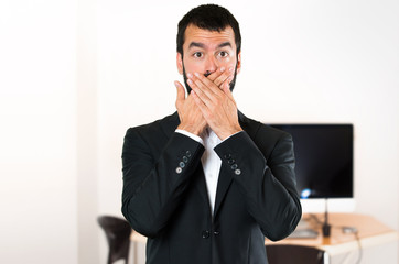 Handsome businessman covering his mouth in the office