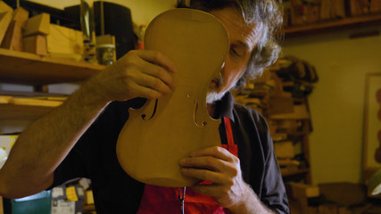 The professional violin master makes a violin with his own hands, uses a clean tree spruce, pine,...