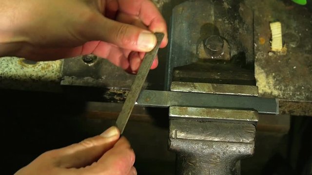 Hand grinding flat bar steel with hand grinder in slow motion top view.
