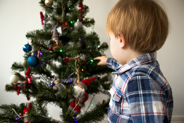 cute little boy playing near Christmas tree. beautiful and cute toddler boy sits near Christmas tree. holidays