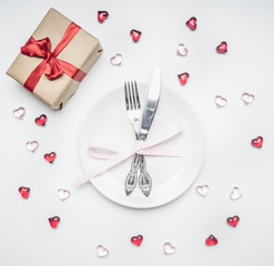 composition for Valentine's day knife and fork tied with ribbon on a plate with decorative hearts