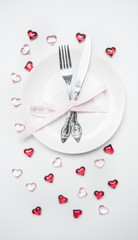 composition for Valentine's day knife and fork tied with ribbon on a plate with decorative hearts