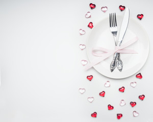 composition for Valentine's day knife and fork tied with ribbon on a plate with decorative hearts