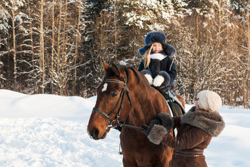 Small girl and mom near horse in a winter