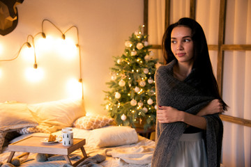 Young romantic girl alone in the room decorated for Christmas.