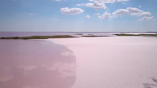 Aerial footage of a pink lake shore with decline and flying low above the solid crystallized salt (4K, 25fps)