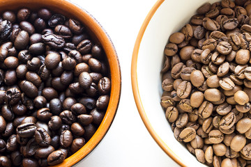 two different types of coffee beans with different roast in cups on a white background