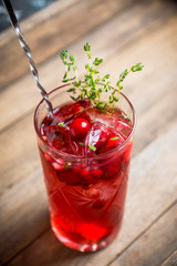 Christmas cocktail with berries and thyme on the rustic background. Selective focus.