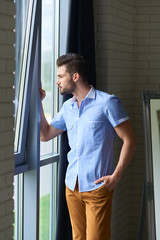 Sexy man model staying and looking at the window