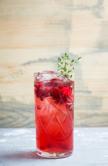 Christmas cocktail with berries and thyme on the rustic background. Selective focus.