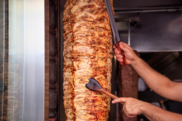 Gyros, doner. Man's hands holding a knife, cutting slices